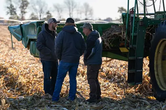 Grower and agronomists discussing plans in harvest field.