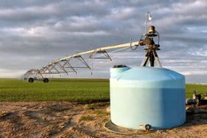 A center pivot sprinkler with attached fertigation tank, watering a wheat field, in the fertile farm fields of Idaho.